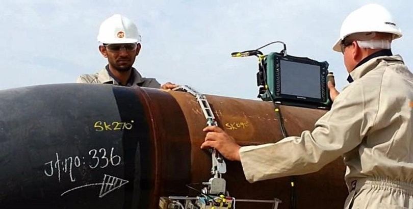 Inspectors running ultrasonic weld testing on a large pipe